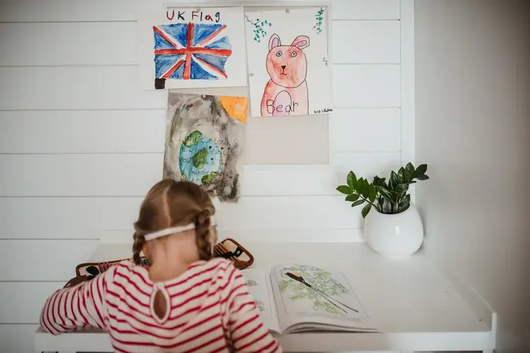 Child drawing next to a wall covered in artwork